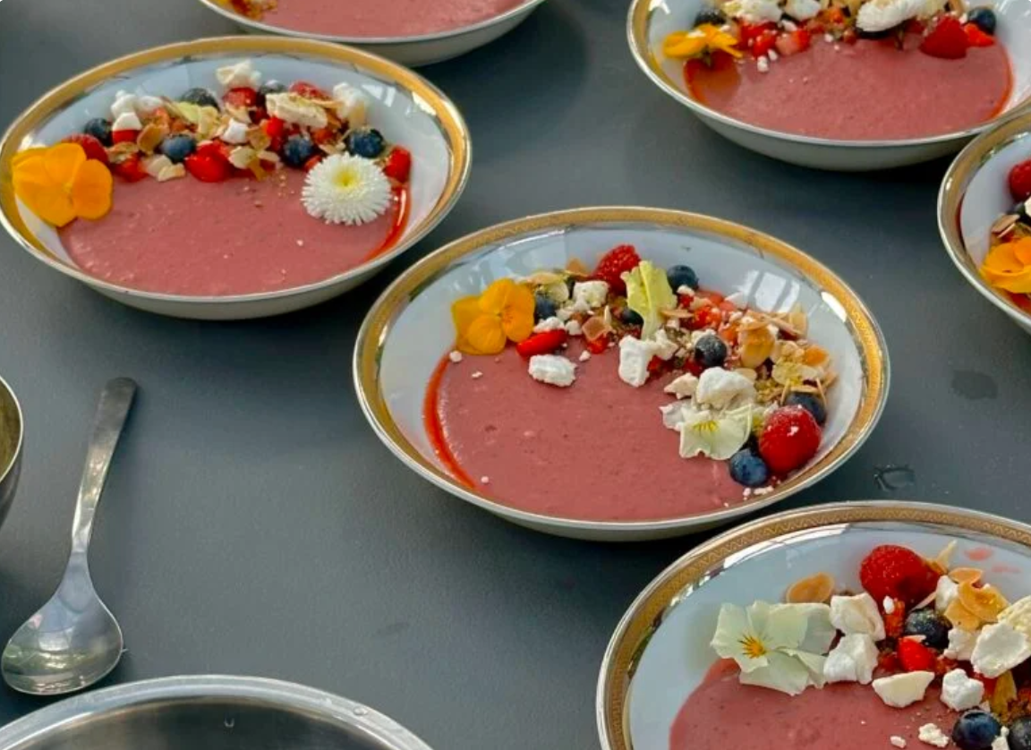 Rožinės spalvos uogų putėsiai (smoothie bowl) lėkštėse, papuošti šviežiomis uogomis, morengais ir valgomomis gėlėmis – Skonio šaukštelis receptai.